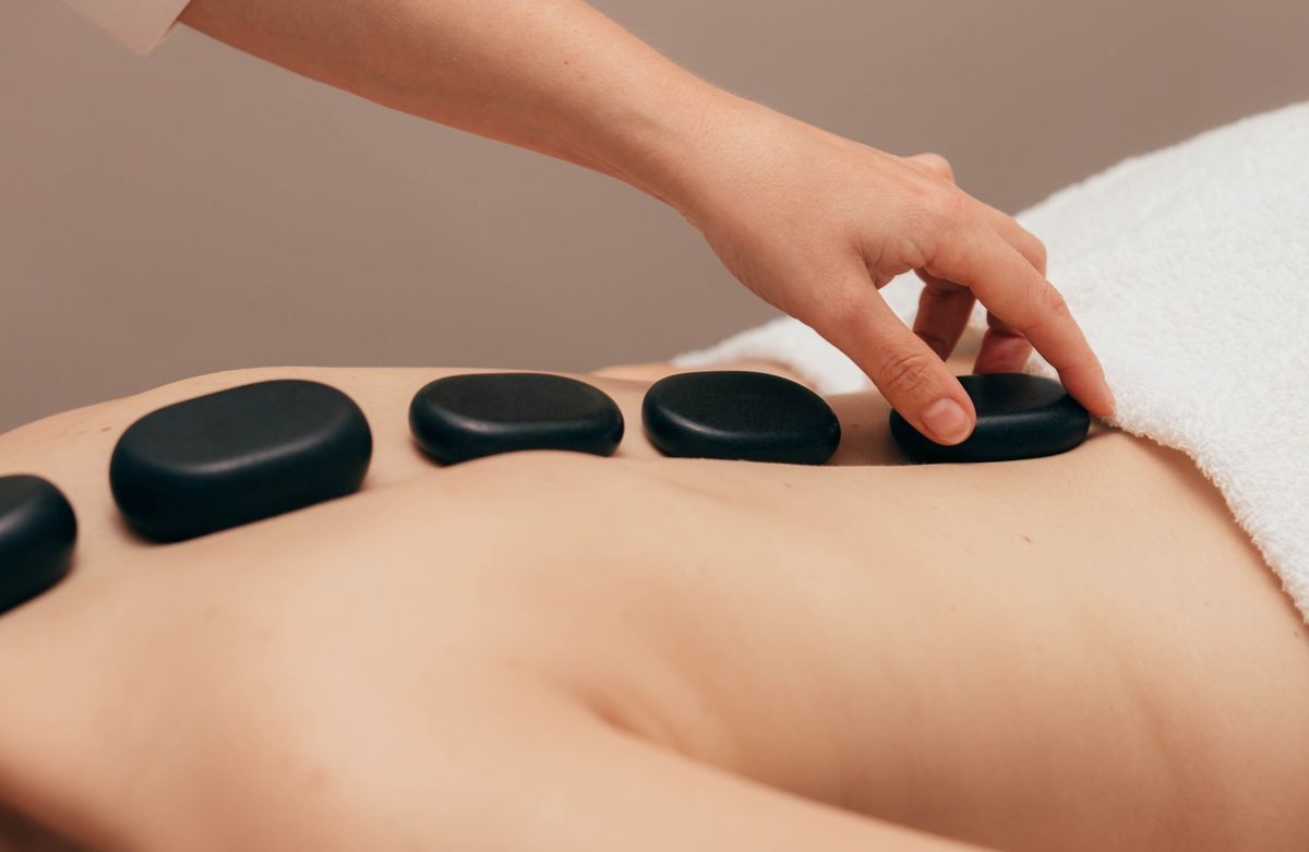 woman receiving hot stones treatment at spa salon. Hot stone massage treatment on human back